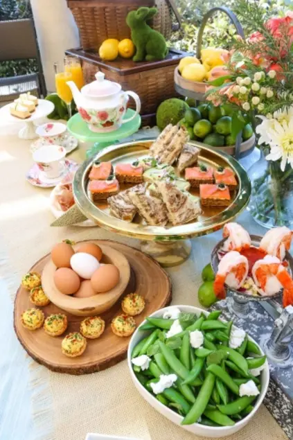 A buffet with various dishes, including finger sandwiches, deviled eggs, edamame.