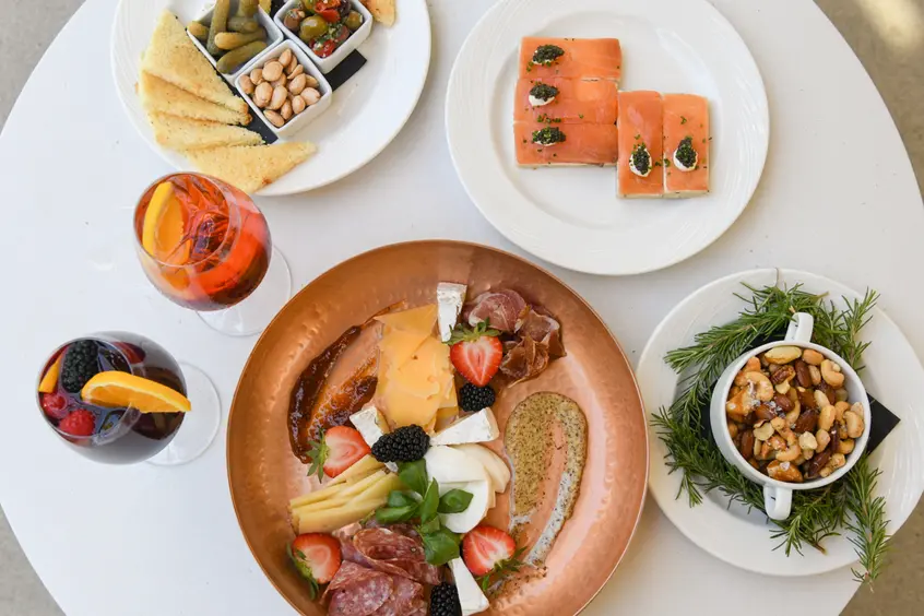 An overhead view of various plates and drinks on a white table.