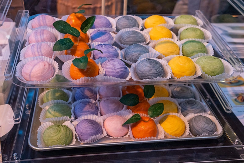 Colorful, round puffed pastries neatly laid out in serving trays.