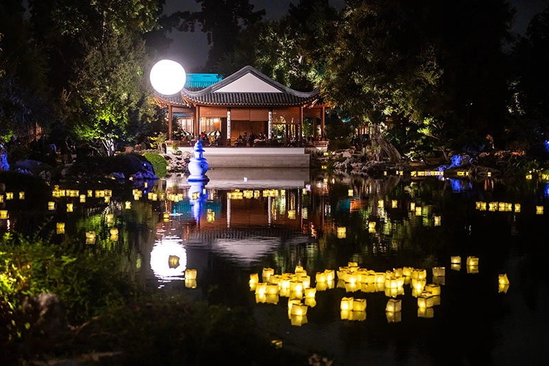 Paper lanterns light up a small lake at night.