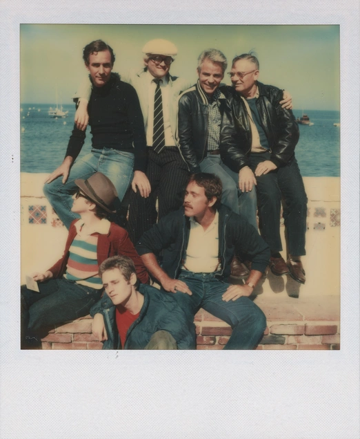 A polaroid photo of a group of men near the ocean.