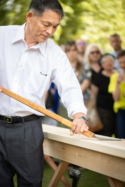 A person holds the blade of a tool against wood.