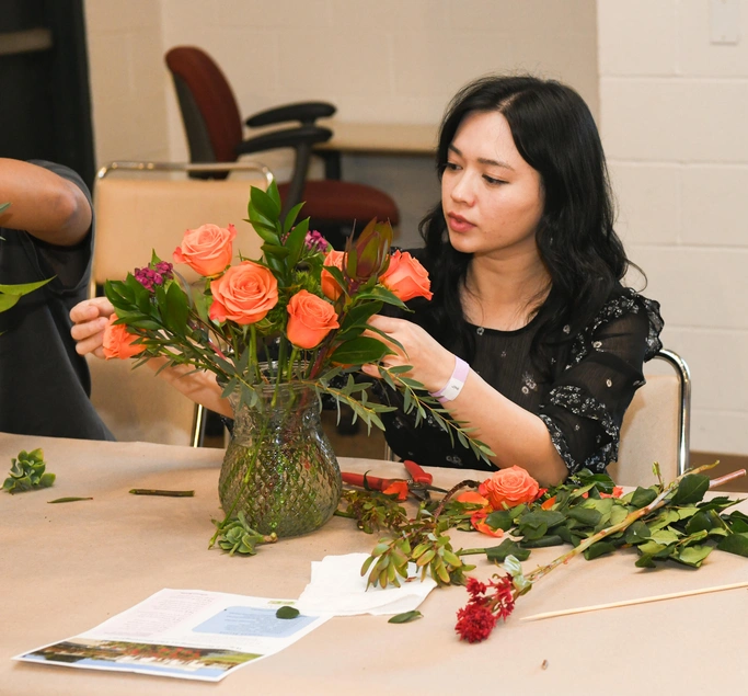 A person fluffs their peach rose flower arrangement.