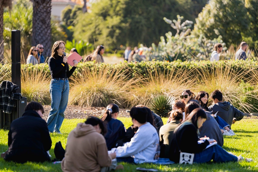 A group of people sit on a lawn.