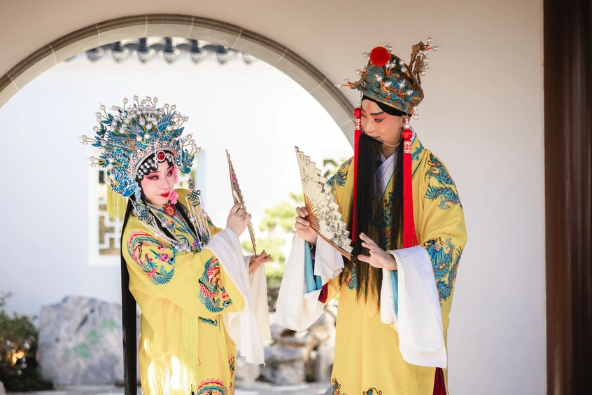 Two people in intricate and colorful costumes interact with eachother.