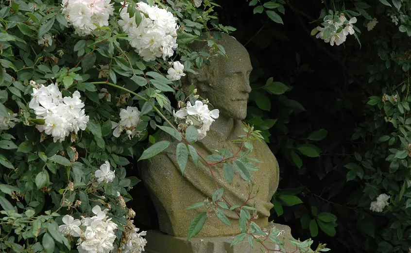 Sculpted bust of William Shakespeare surrounded by white roses