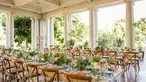 Long rows of wooden tables set up with spring flower centerpieces and glassware.	