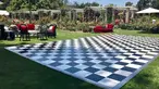 A black and white checkered dance floor set among red velvet couches in an outdoor rose garden.