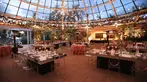 Dinner tables and stringed lights set up under a glass dome.