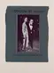 Dark gray-blue book cover with a black and white image of two people in fancy clothes, posing for a photo.