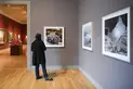 A person looks at a framed photo on a gallery wall.