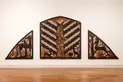 Three carved wood panels on a wall that form a semicircle.