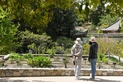 Two people in hats look at a plant bed with small green plants.