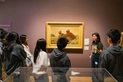 A group of young people gathered around a painting.