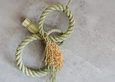 A twisted wreath in a figure-eight form, created from stems of a rice plant with hulls on.