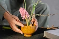 A Japanese-style floral arrangement in a wooden bowl.