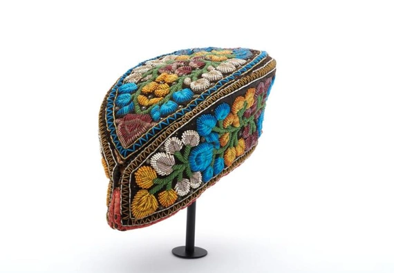 Black velvet cap in the shape of a pointed oval, with beadwork in blue, white, green, yellow, and red forming flowers and stems all over; made by a Haudenosaunee woman. 