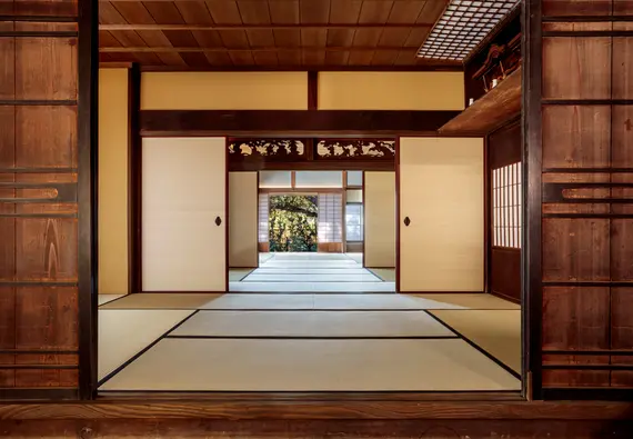 View from inside a traditional Japanese home with tatami mats and sliding walls open to a private garden.