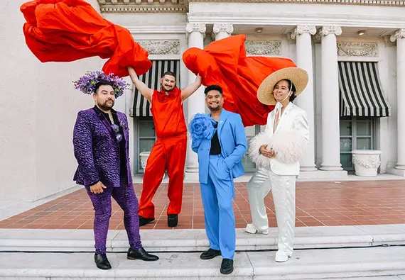 Four people pose in colorful outfits.