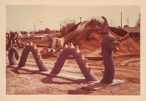 A faded 1980s photograph of a sea serpent play structure among mounds of under-construction dirt.	