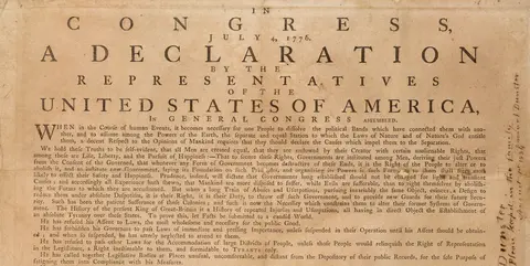 A tan parchment paper with small printed text, a large title reads "In Congress, July 4, 1776, a declaration by the representatives of the United States of America, in General Congress assembled"