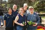 Five people posing for camera, some holding small plants.