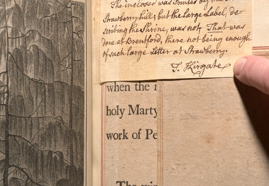 An open book with layers of papers on the same page, including an illustration and printed and handwritten text.