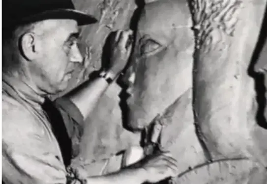 black and white photo of a man in a fedora looking closely at a sculpture of a person