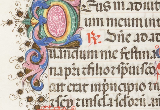 A detail view of an illuminated book with colorful ornate lettering.