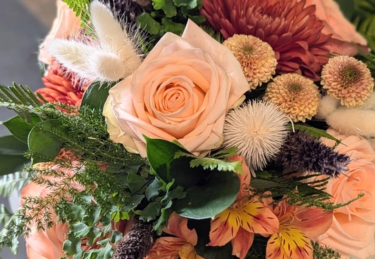 A bouquet of peach-colored roses, chrysanthemums, and other fresh flowers.