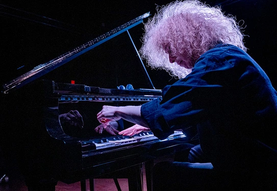 A stylized photo of a musician playing a piano.