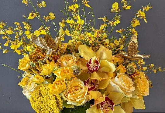 A flower arrangement of yellow and gold Cymbidium and Oncidium orchids.