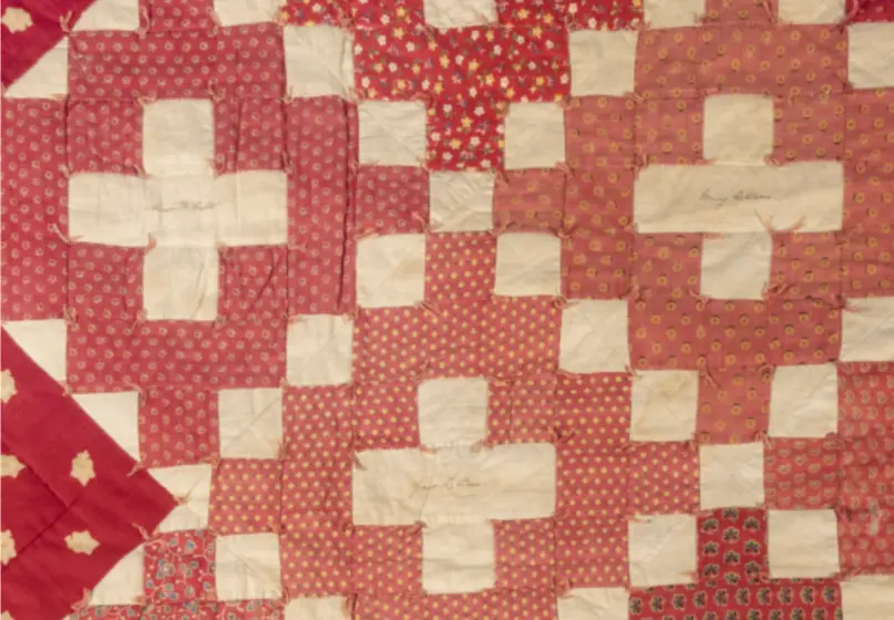 Red fabric quilt with arrangment of squares at the center, each containing a white cross with a name written in script.