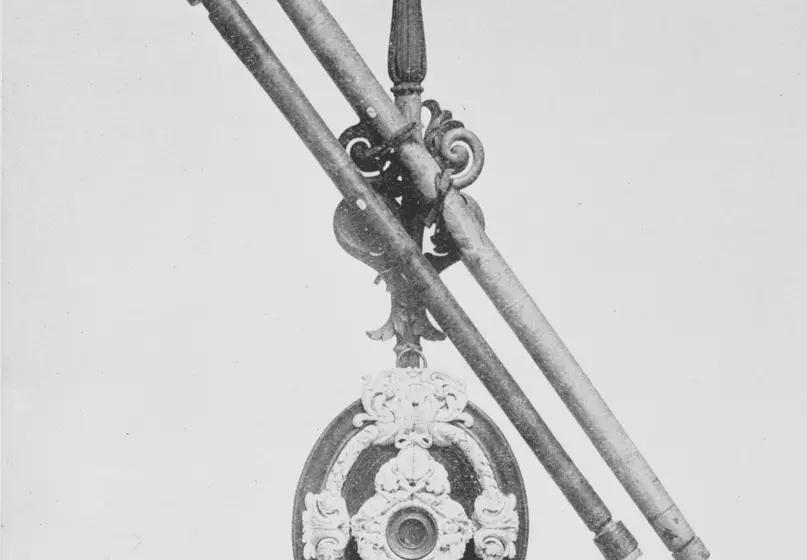 A black and white photograph of a telescope with two barrels and with decorative filigree 