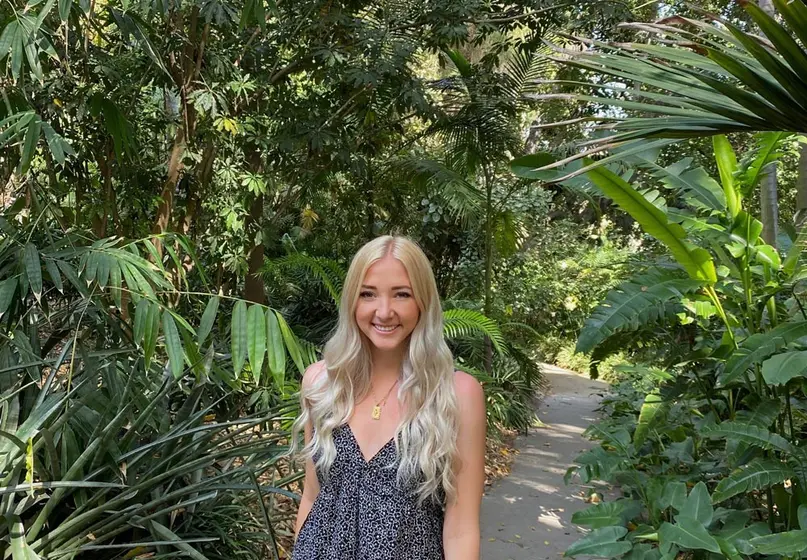 A college student walks through a garden of tropical plants.