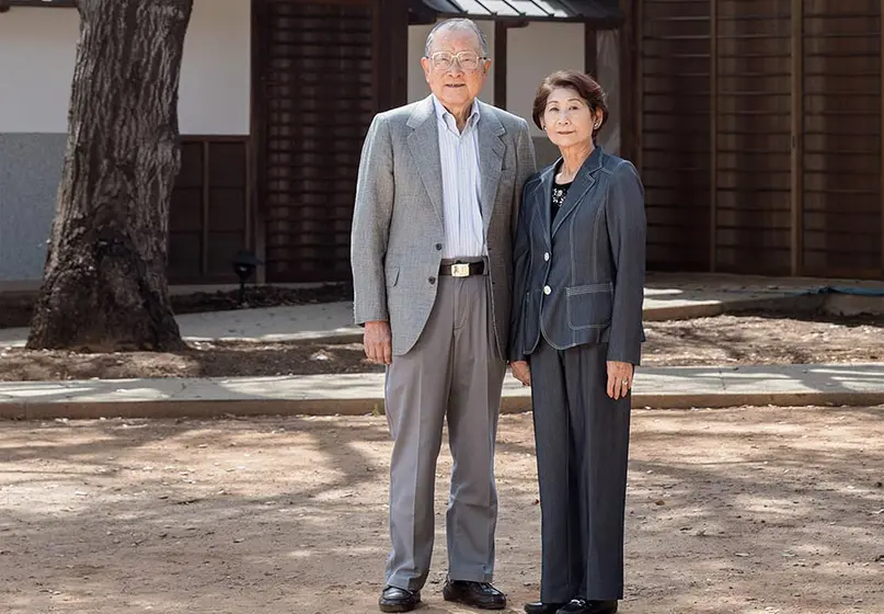 Two adults standing in front of Japanese house