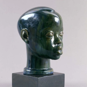 Three-quarter profile view of a small blue/green glazed terracotta sculpture of a young Black boy's head and neck.