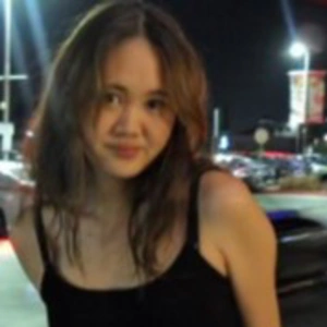 A person in a black tank top, outside at night.