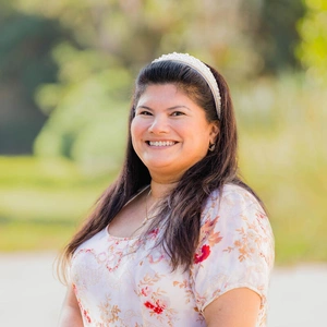 A smiling person in a sunny garden.