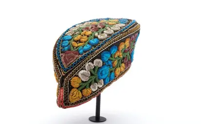 Black velvet cap in the shape of a pointed oval, with beadwork in blue, white, green, yellow, and red forming flowers and stems all over; made by a Haudenosaunee woman. 