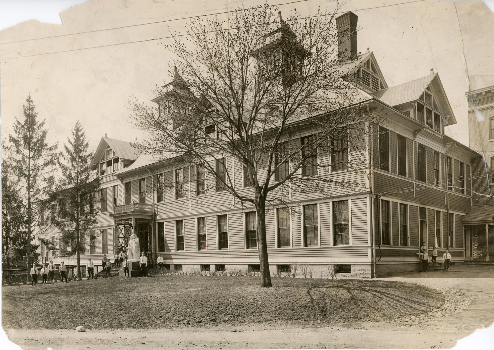 Black and white photo of a large, simple wooden building from the 1800s with rectangular windows on the front and sides.