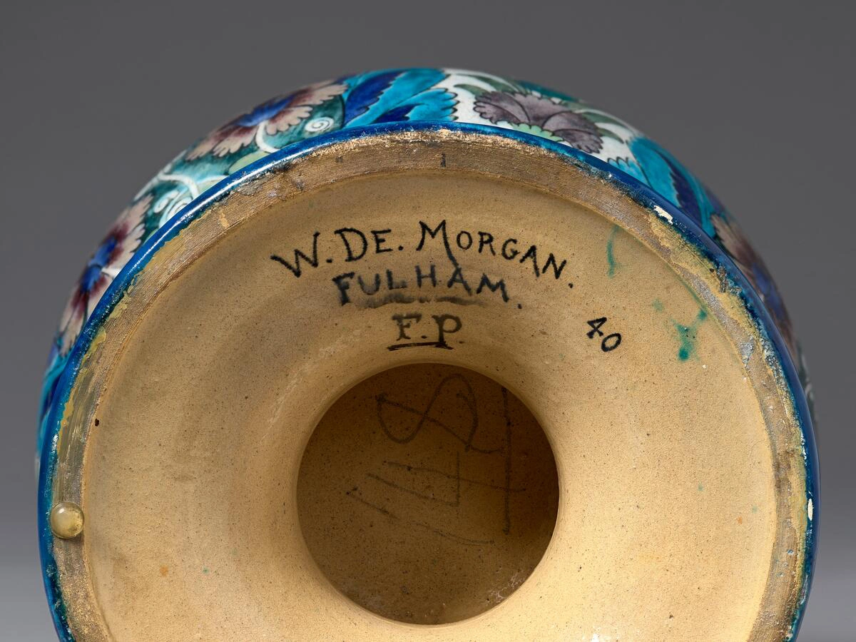 A view of the bottom of a ceramic vase, with text that reads, “W. De. Morgan. Fulham. F.P. 40.”