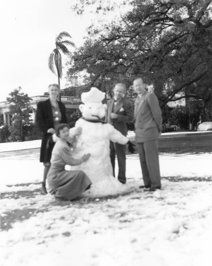 Employees Dorothy Bowen (standing), unidentified woman, Graydon Spalding, and Irwin Morrkish pose with a snowman. (Jan. 11, 1949)