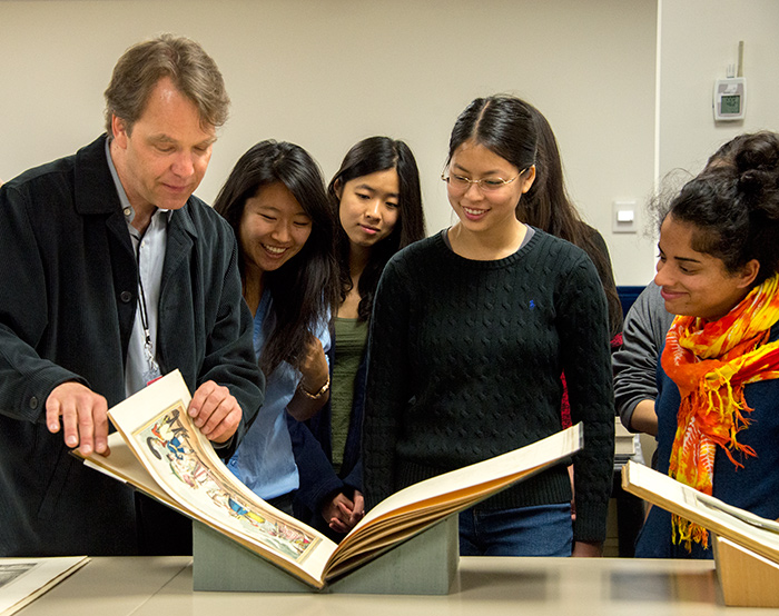 During a visit to The Huntington, Caltech professor Kevin Gilmartin shows his English 127 students a book illustrating “monstrosities of fashion.” Photo by Kate Lain.