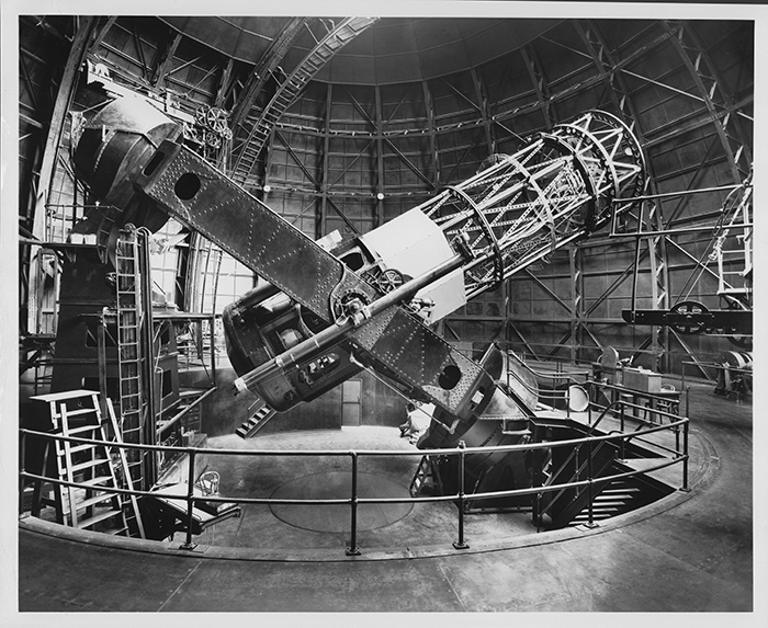The Hooker 100-inch reflecting telescope, ca. 1940, side view with tube 40 degrees from horizontal. The chair of astronomer Edwin Hubble (1889–1953), on an elevating platform, is visible at left. Photo by Edison Hodge. The Huntington Library, Art Collections, and Botanical Gardens.