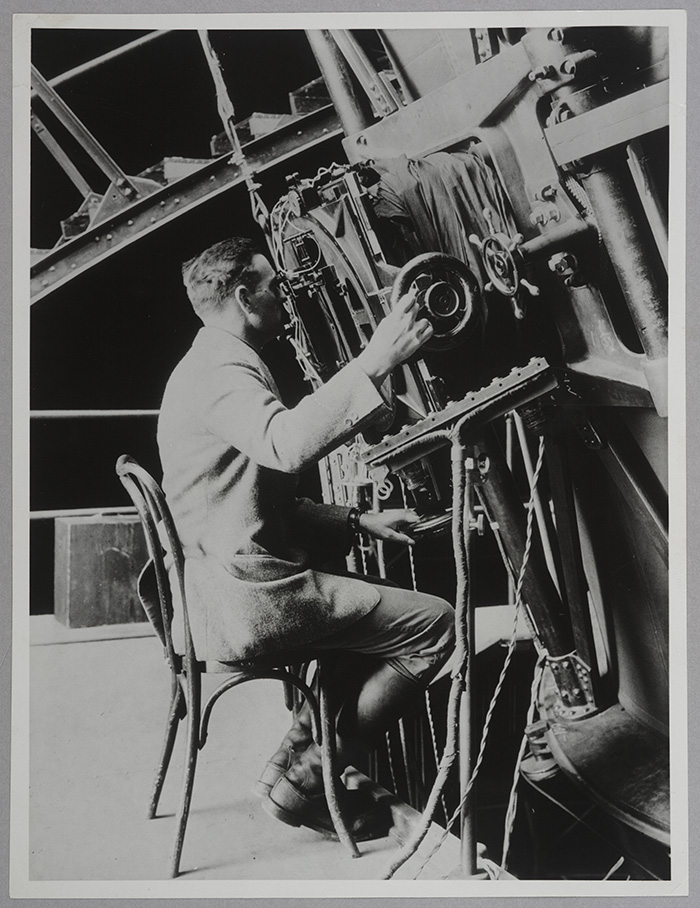 Edwin Hubble (1889–1953), seated at the Hooker 100-inch reflecting telescope, ca. 1924. Unidentified photographer. The Huntington Library, Art Collections, and Botanical Gardens.