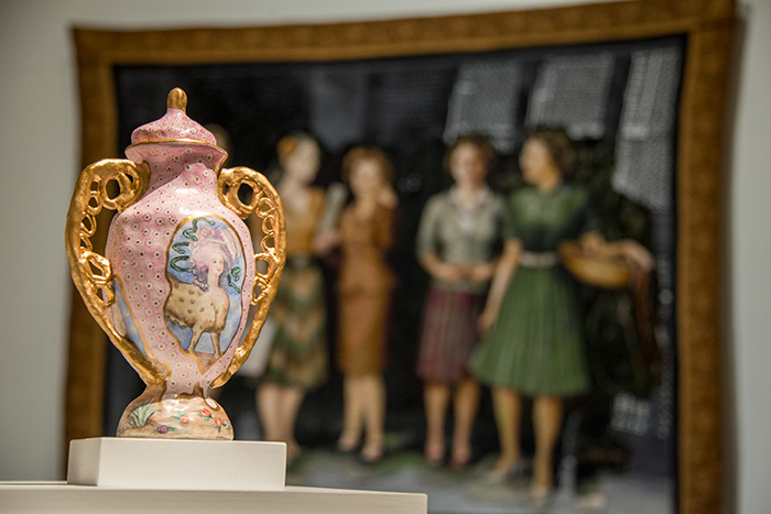 The Three Graces and Marie Antoinette, a new porcelain and enamel vessel by Juliana Wisdom, sits atop a pedestal in "COLLECTION/S: WCCW/five at The Huntington." Soyoung Shin's tapestry 24,000 BCE–1992 CE, made from a design by Melanie Florio, hangs on a nearby wall. Photo by Kate Lain.