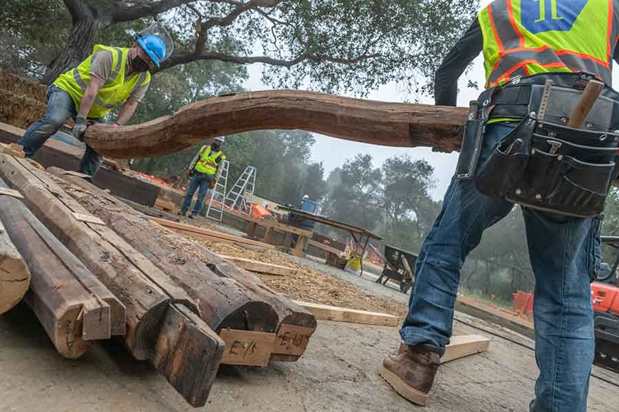 Artisans from Japan have joined the construction team, working alongside the American contractors. Pictured here, two wood craftsmen move one of the original notched roof beams in preparation for installation. The Huntington Library, Art Museum, and Botanical Gardens. Photo by John Diefenbach.