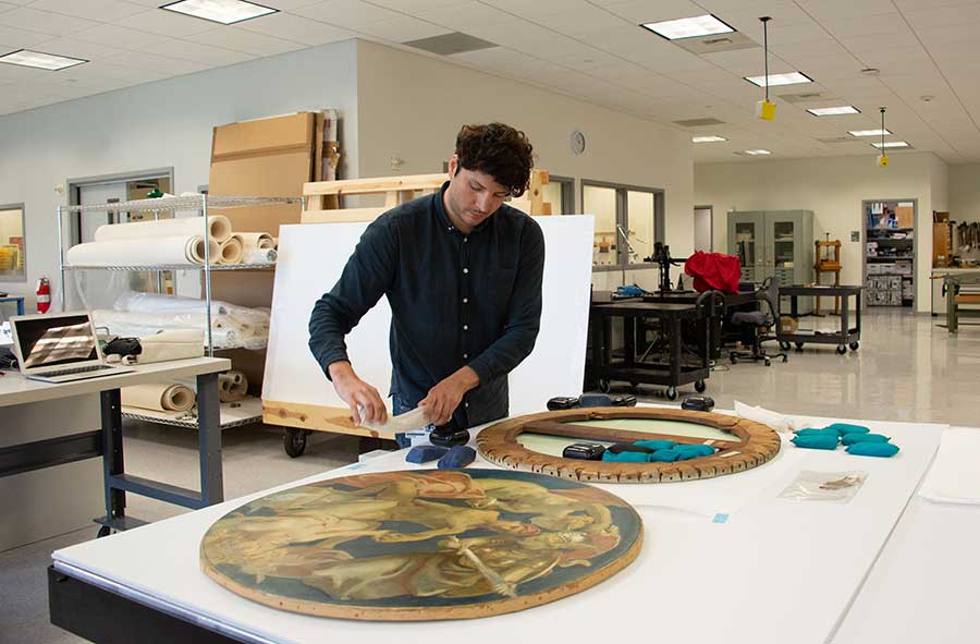 Jose Luis Lazarte, a research scholar in paintings conservation at The Metropolitan Museum of Art in New York City, weights the back of Sargent’s Sphinx and Chimera. Photo by Deborah Miller.