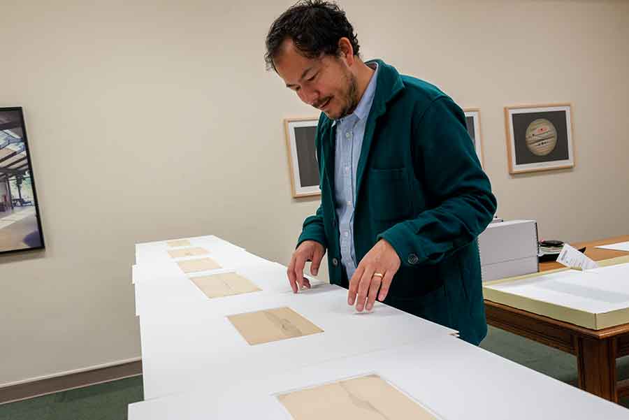 Rosten Woo studies landscape drawings produced during an expedition led by John Russell Bartlett (1805–1886). Bartlett was hired to draw the border between Mexico and the United States after the Mexican American War in 1846. Photo by Kate Lain.